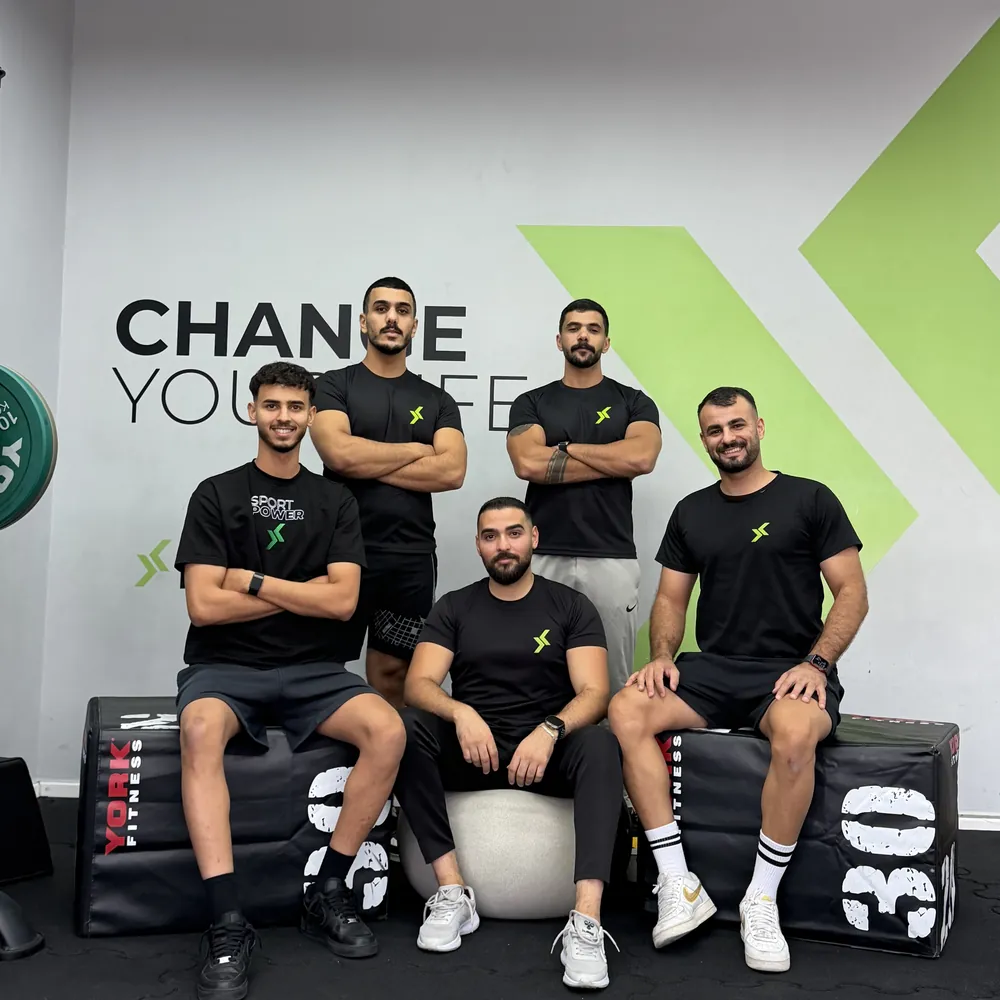 The Sport Power coaching team in front of the CHANGE YOUR LIFE wall